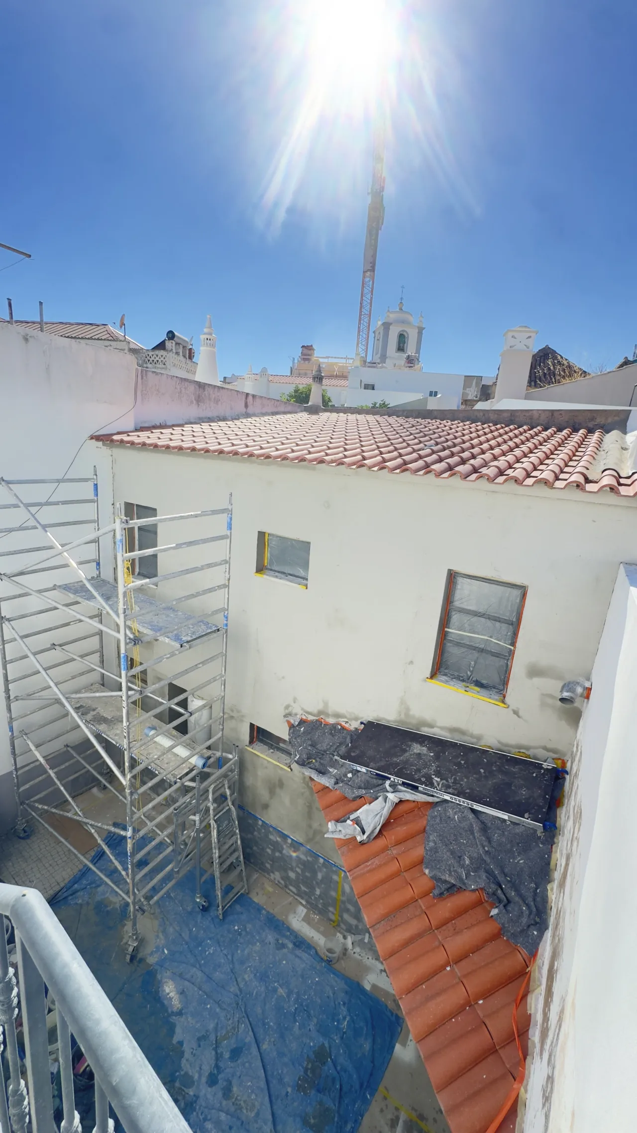 Courtyard of the house with scaffolding up and the façade already made good, with the Lagoa church tower behind
