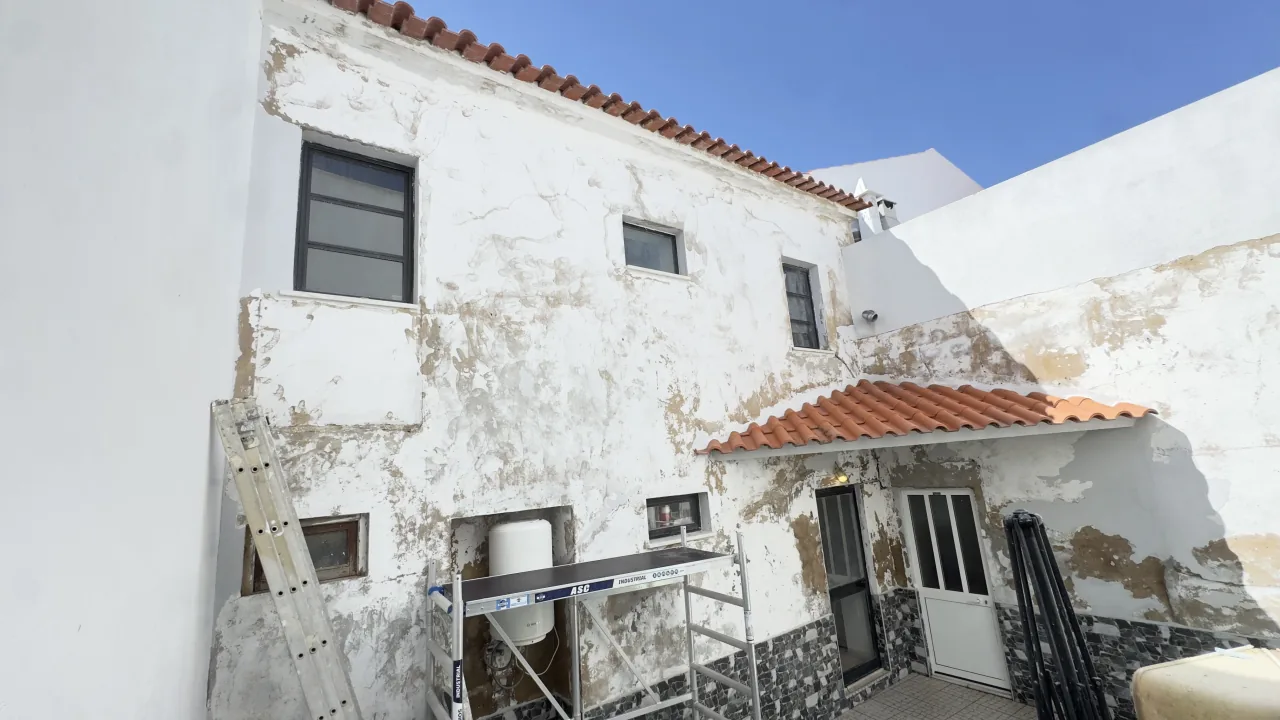 Façade with weathered render and peeling paint, before the work