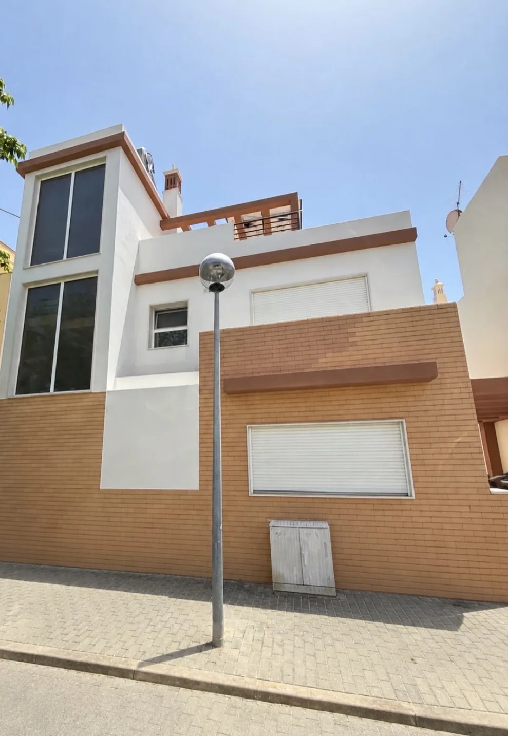 Three-storey house with white render, brown bands and brick-coloured ceramic cladding