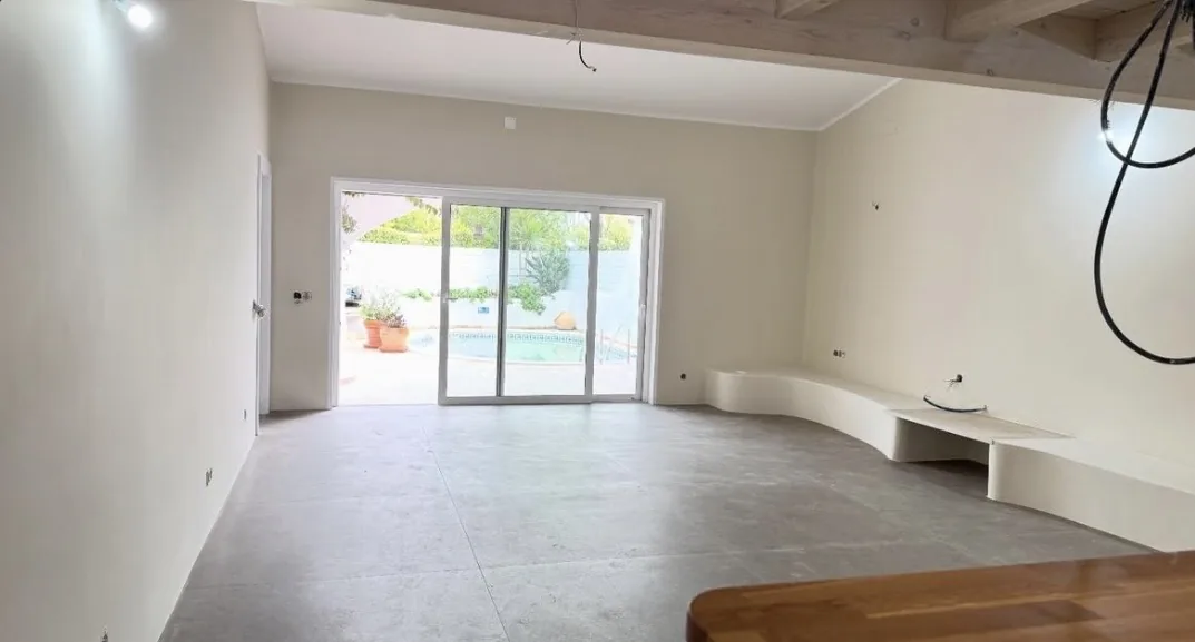 Refurbished living room in a villa in Vale do Lobo, with white walls, a curved built-in bench and a sliding door to the pool