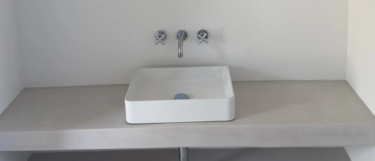 Richimi microcement worktop and walls in a bathroom in Boliqueime: one continuous surface, no joints.